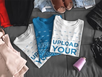 Mockup of Three T-Shirts Lying Folded on a Bed