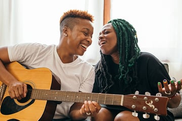 Happy lesbian couple playing the guitar and singing