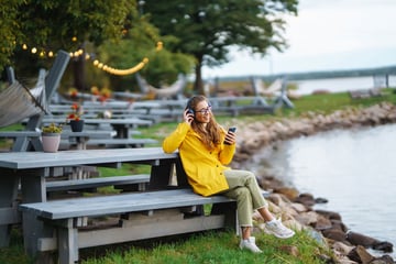 woman on a bench listening to her phone with headphones
