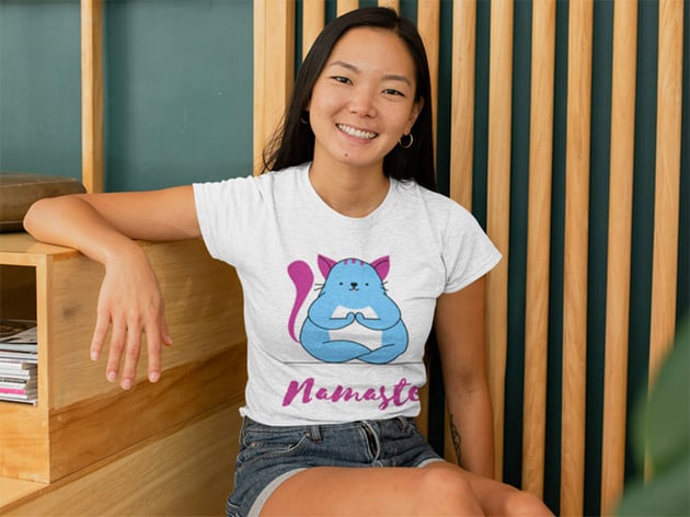 Mockup of a Woman with a Heather T-Shirt Sitting Against a Wooden Background