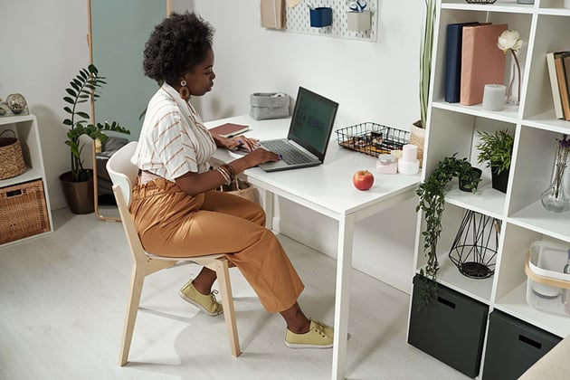 Young contemporary businesswoman networking by desk at home