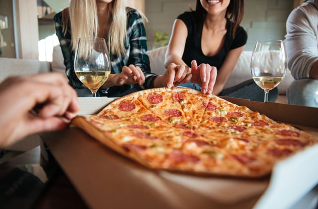 Group of friends eating big pizza and drinking