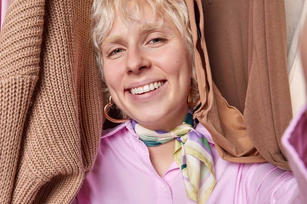 Blonde woman exudes positivity confidence as stands amidst delightful assortment of clothes on