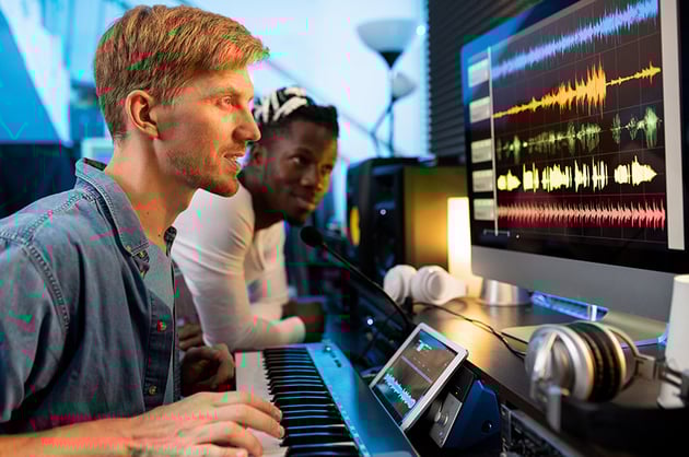 Young man with pianoboard looking at computer screen during work in studio